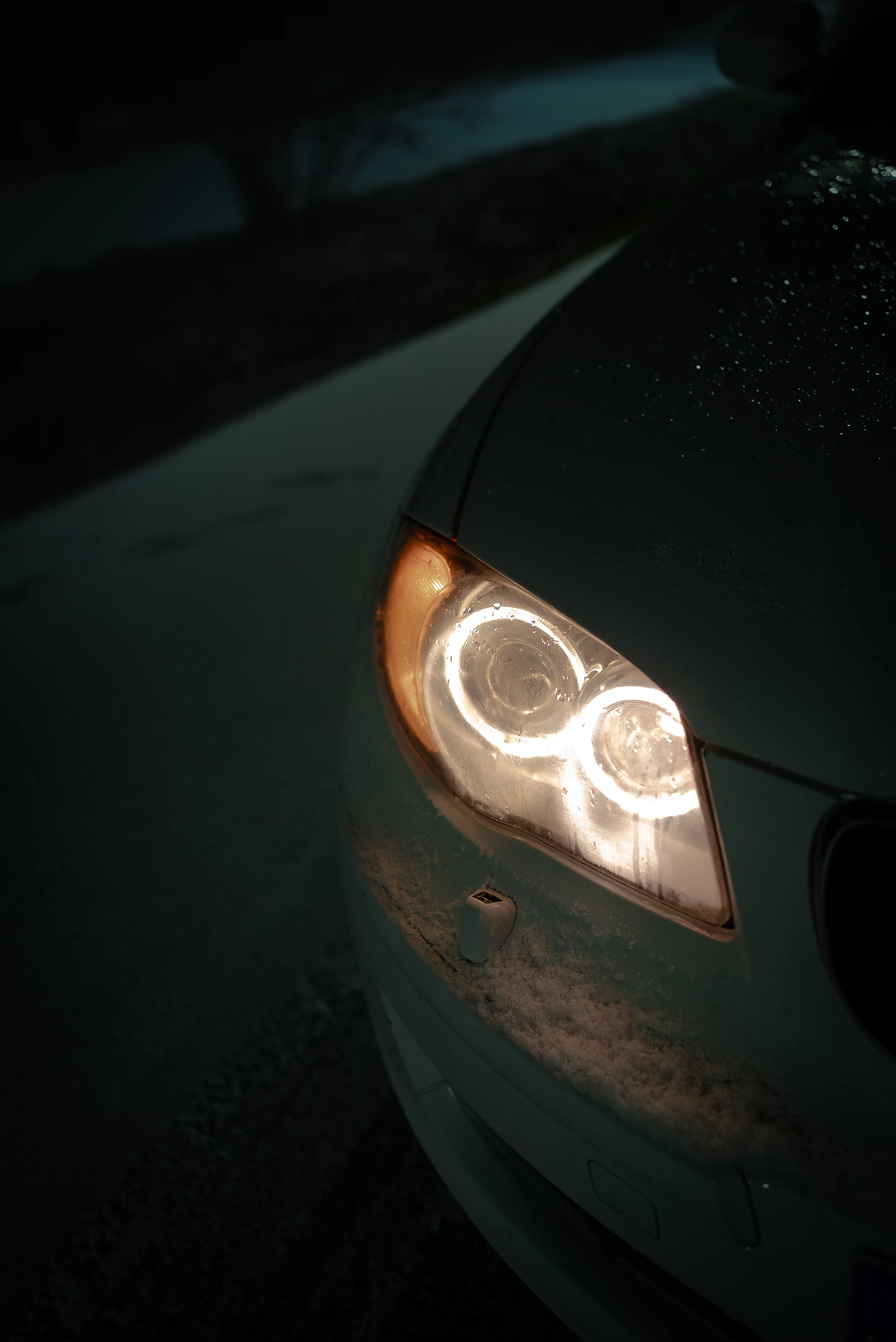 Phare avant BMW allumé dans la neige et la nuit