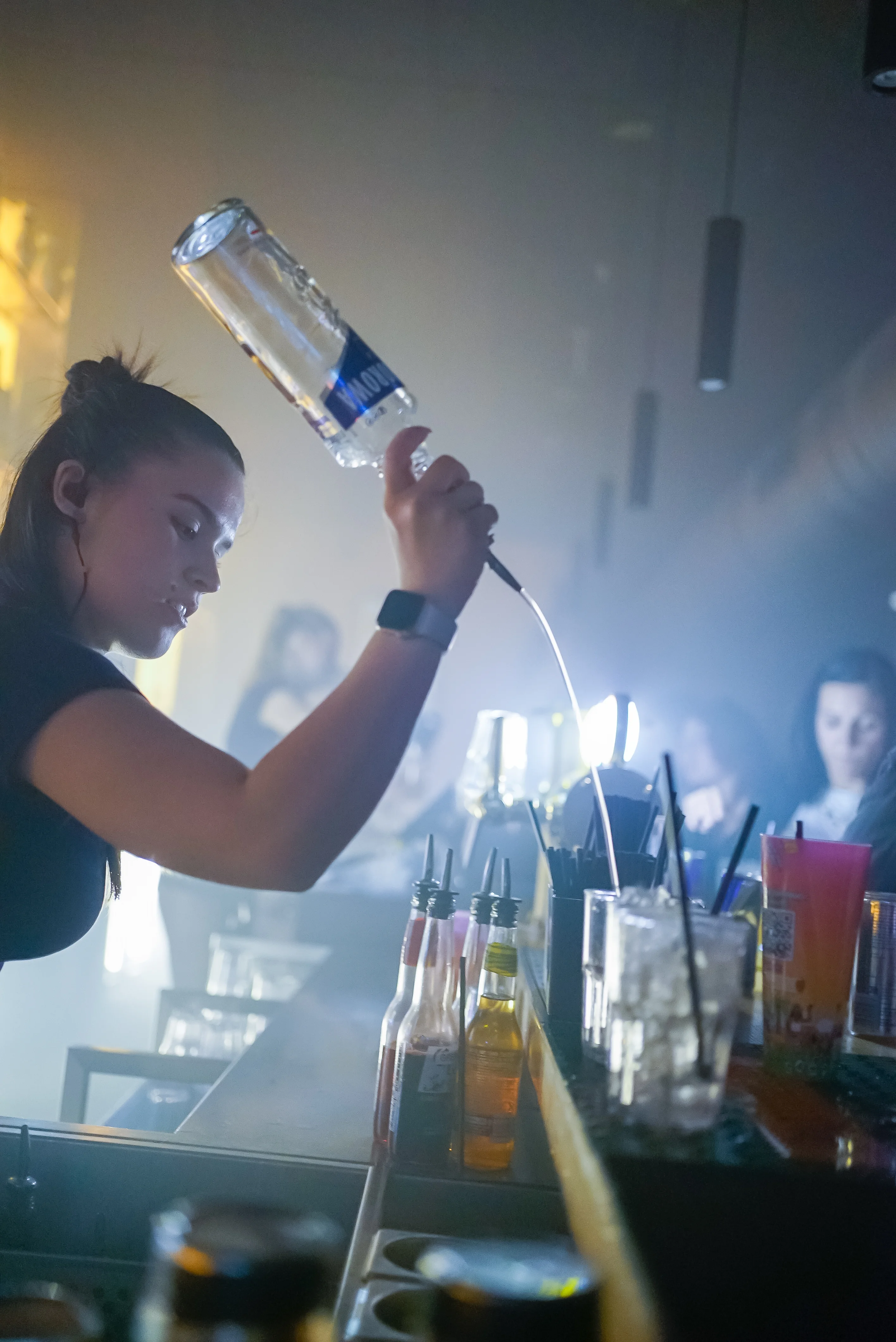 Barmaid servant une bouteille dans les volutes de fumée et contre-jour