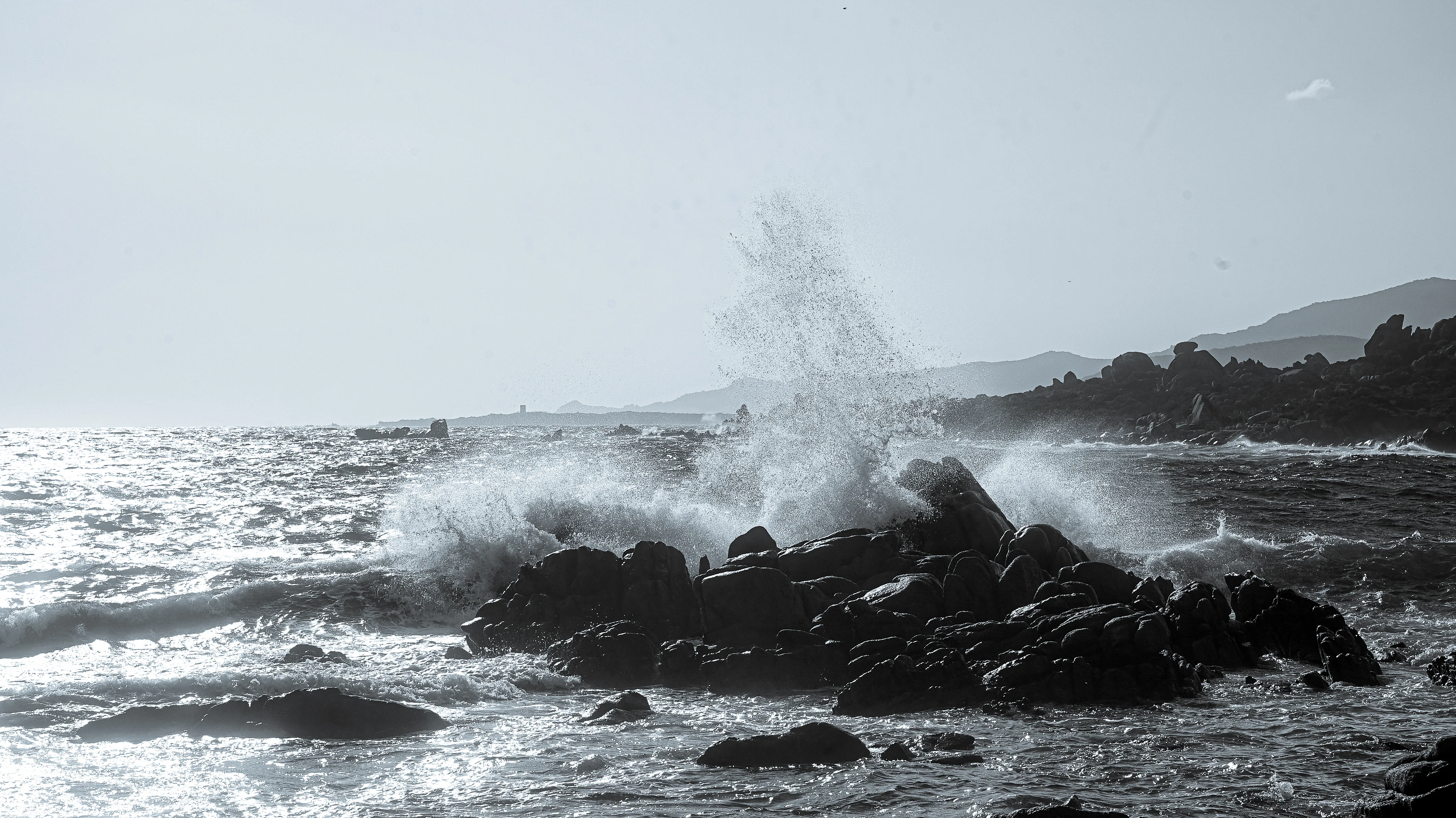 Photographie marine de vagues se brisant sur les rochers en noir et blanc