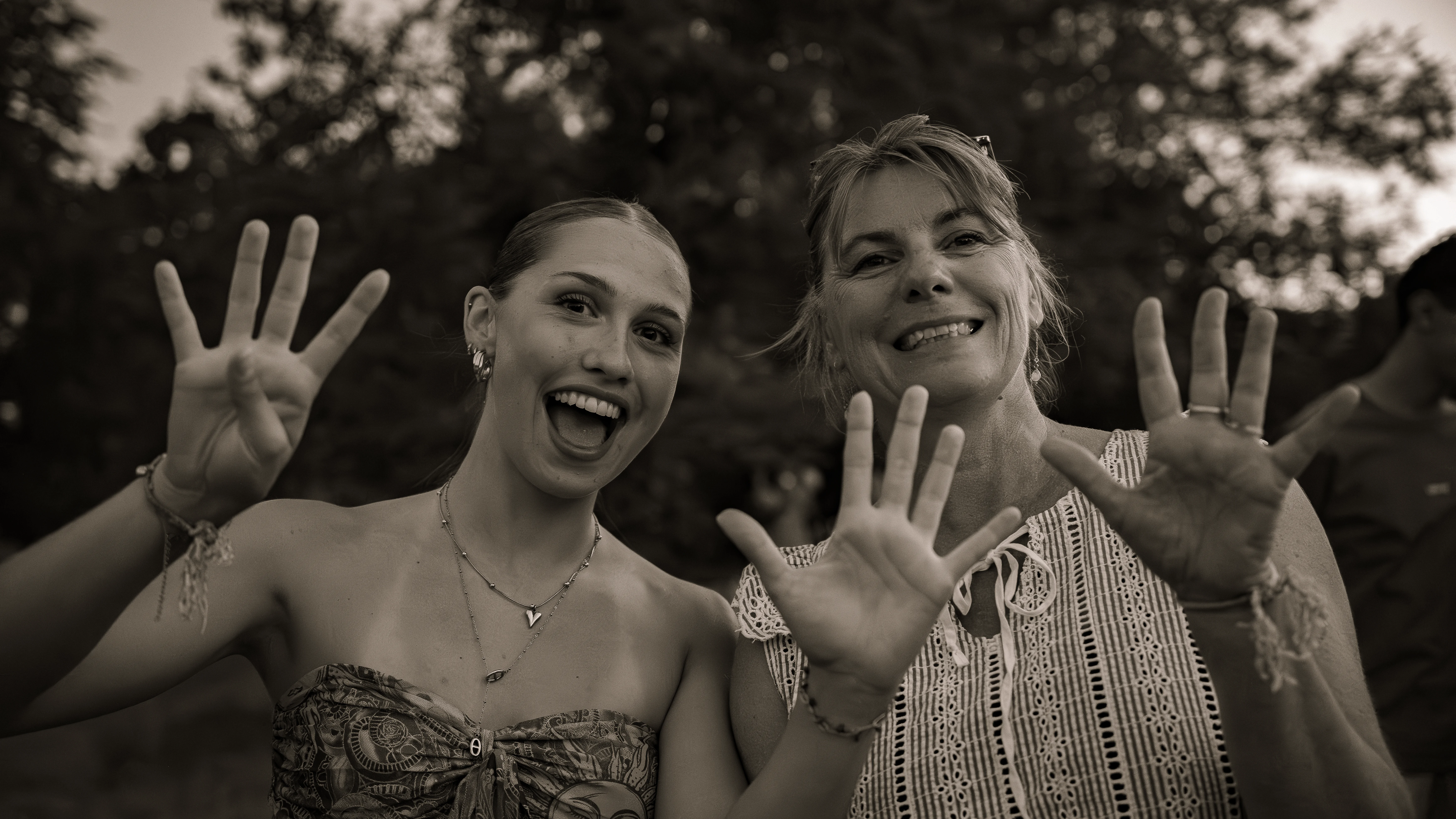 Portrait complice de deux femmes souriantes saluant la caméra en noir et blanc