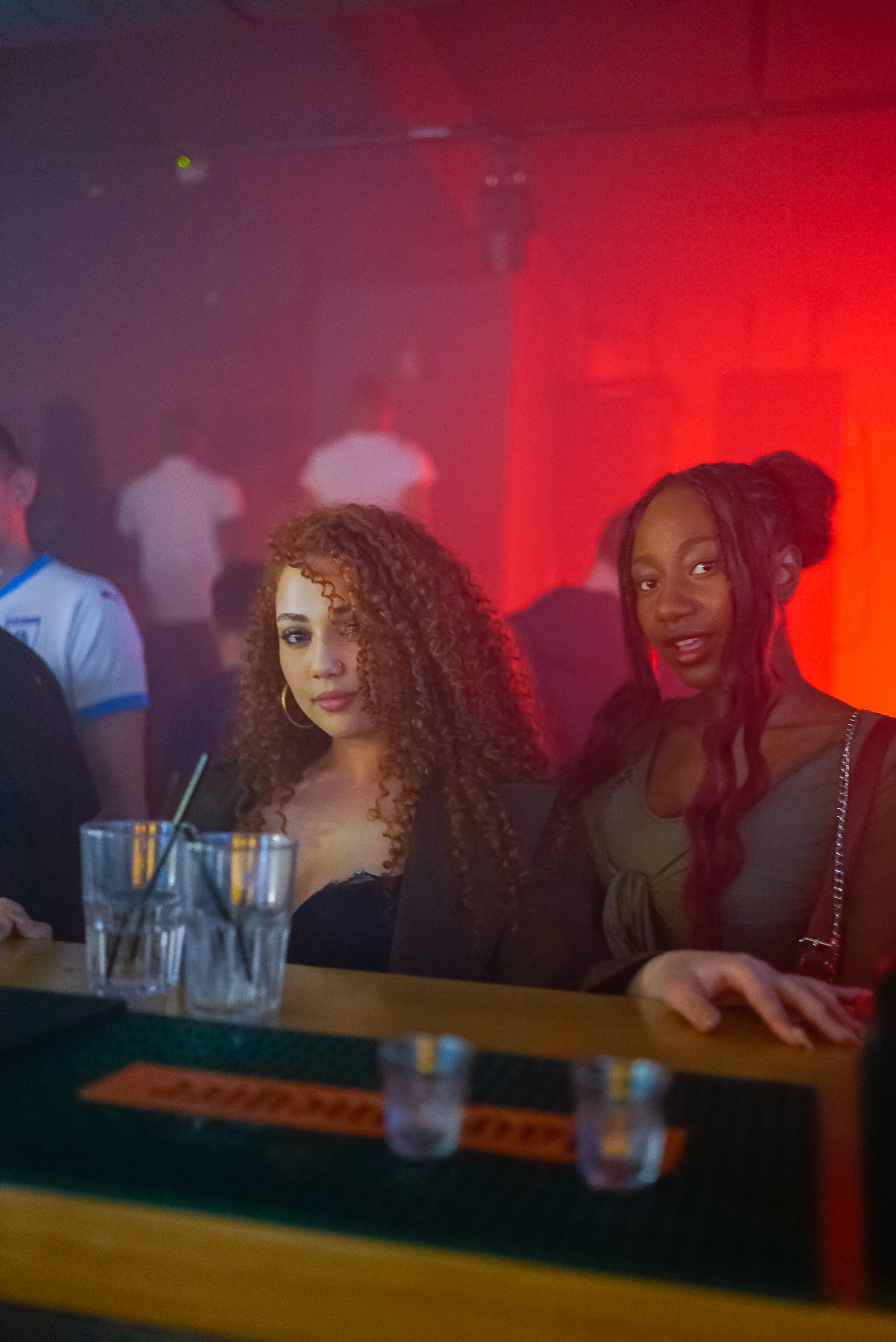 Portrait de deux jeunes femmes au bar sous lumière feutrée
